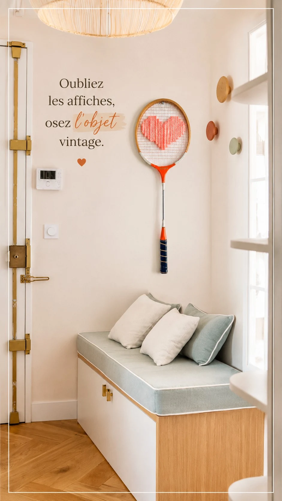 Raquette vintage au cœur rose corail brodé au-dessus d’une banquette dans une entrée lumineuse