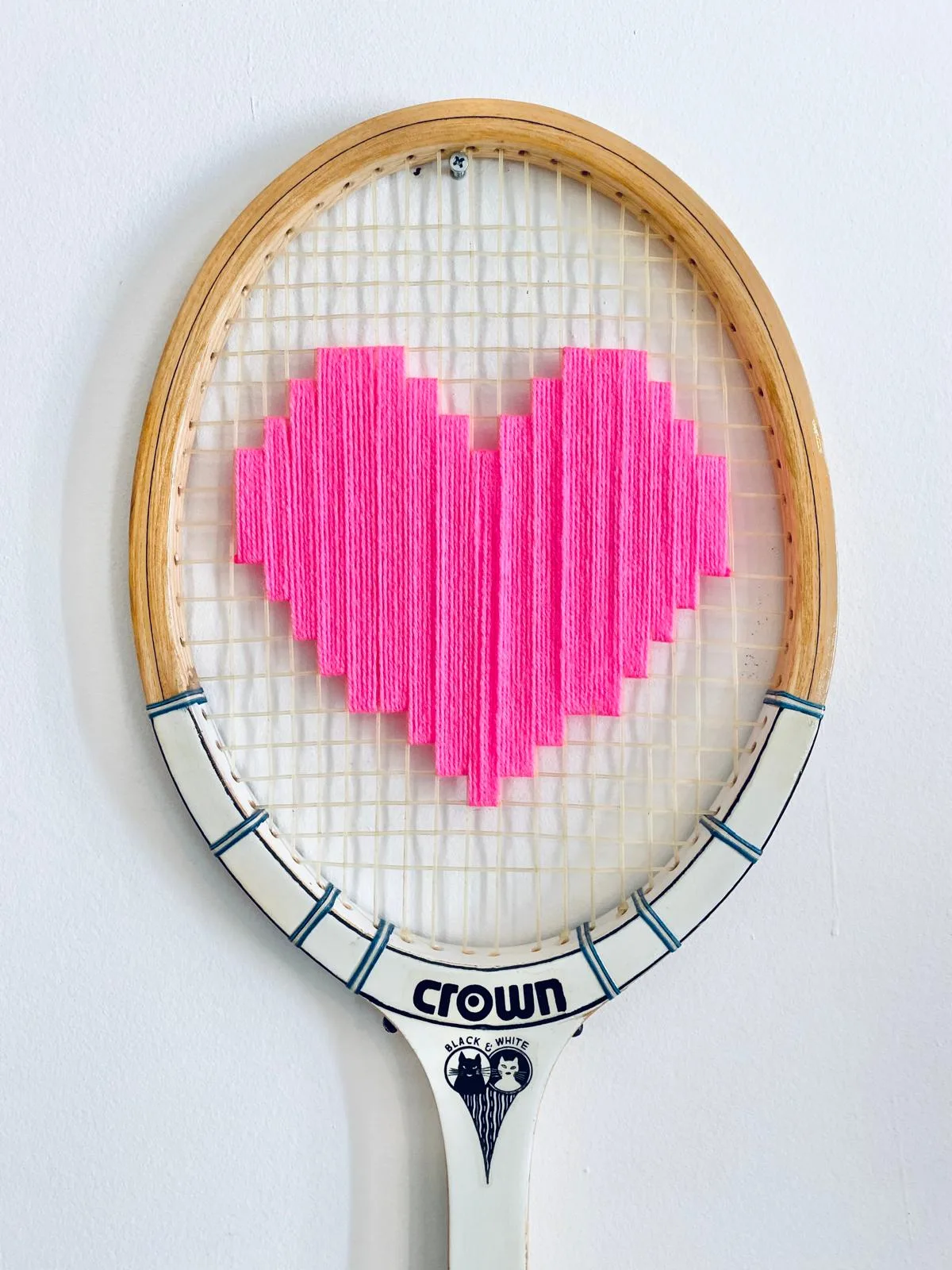 Gros plan sur le cœur rose pixel brodé à la main dans la même raquette Crown
