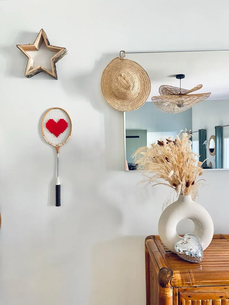 Raquette de badminton vintage au cœur pixel rouge, au col blanc et au manche noir, accrochée au mur dans la décoration de Charlotte