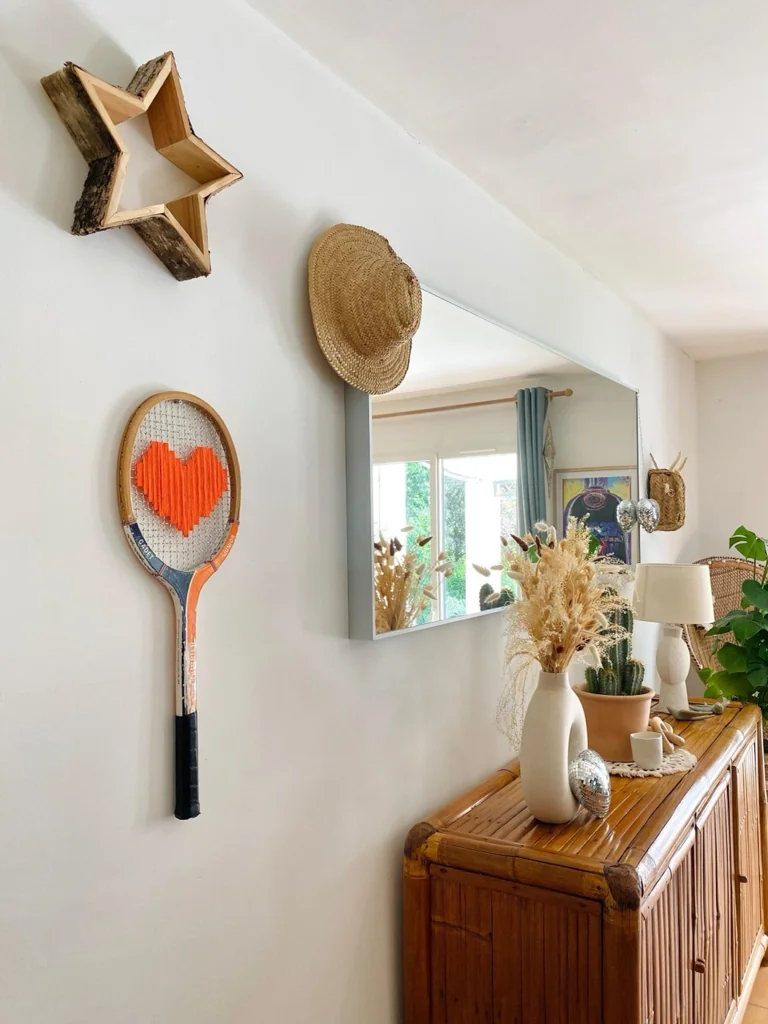 Raquette de tennis vintage au cœur pixel orange, accrochée au mur dans la décoration de Charlotte